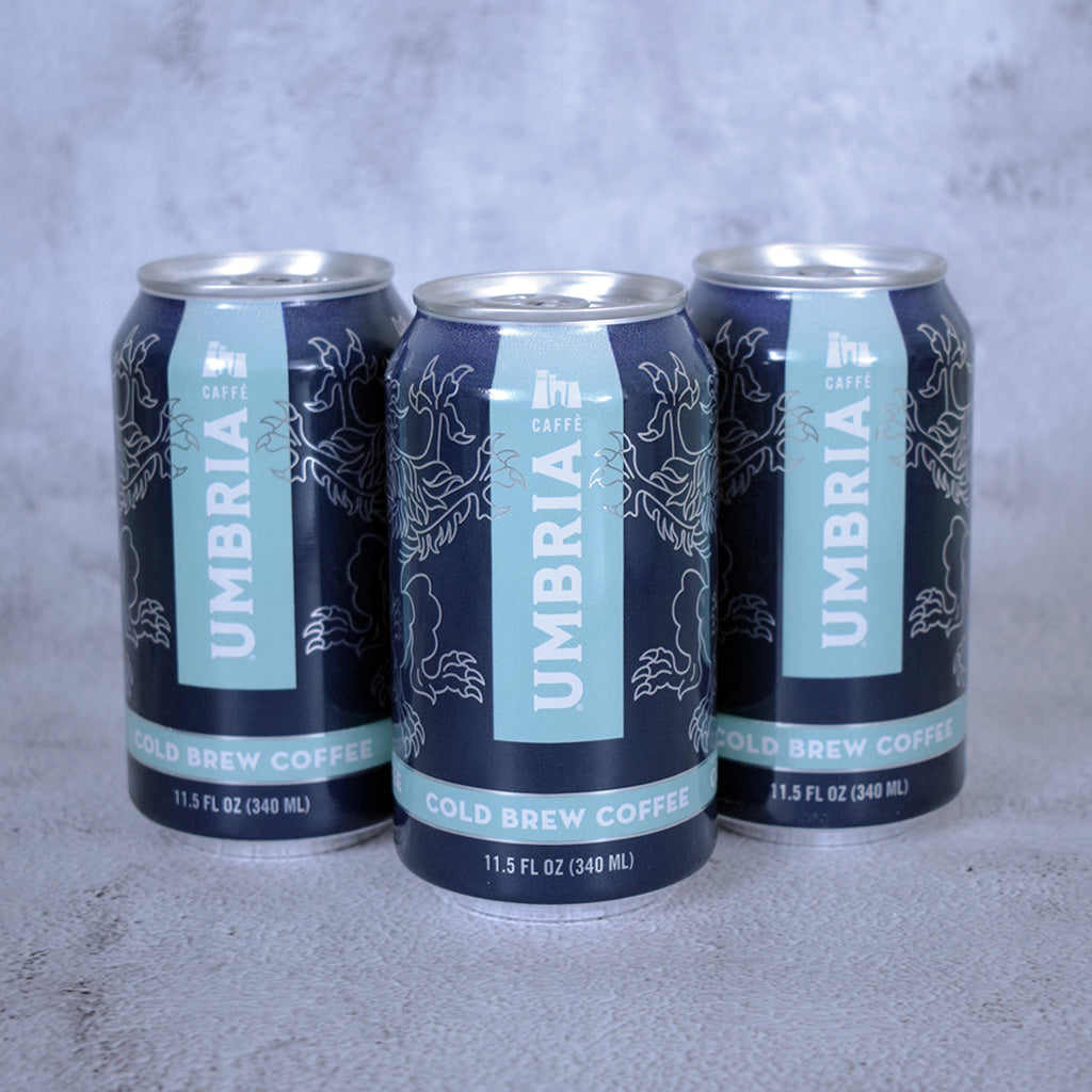 Three cans of Umbria Cold Brew Coffee on a gray background