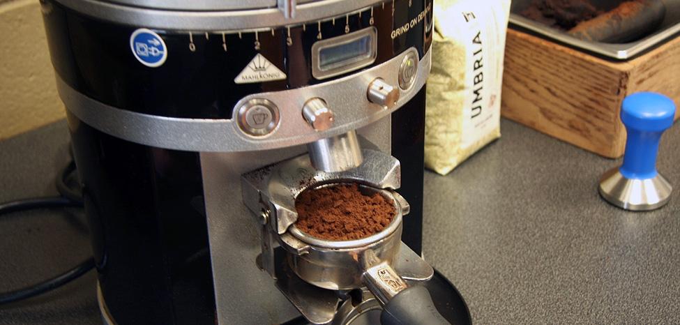 a portafilter with ground coffee at the grinder