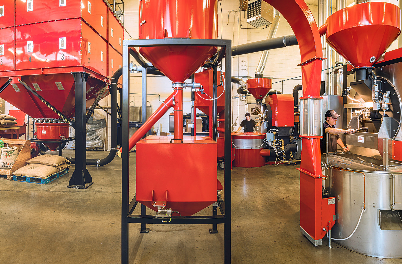 inside our seattle roastery, showing Emanuele at the roaster, and red roasting and green coffee machines